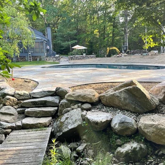 In-progress gunite pool construction with rebar structure and forest backdrop