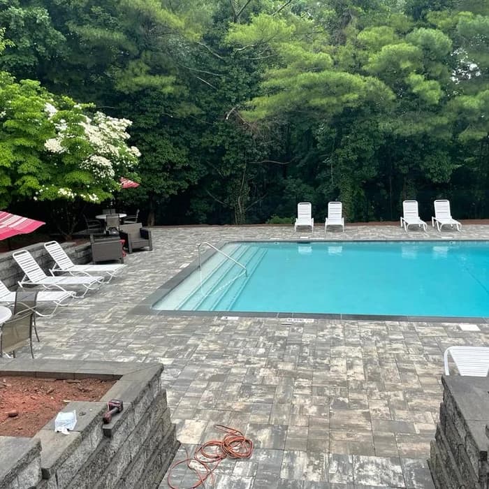 Rectangular pool with paver patio, lounge chairs, and retaining walls