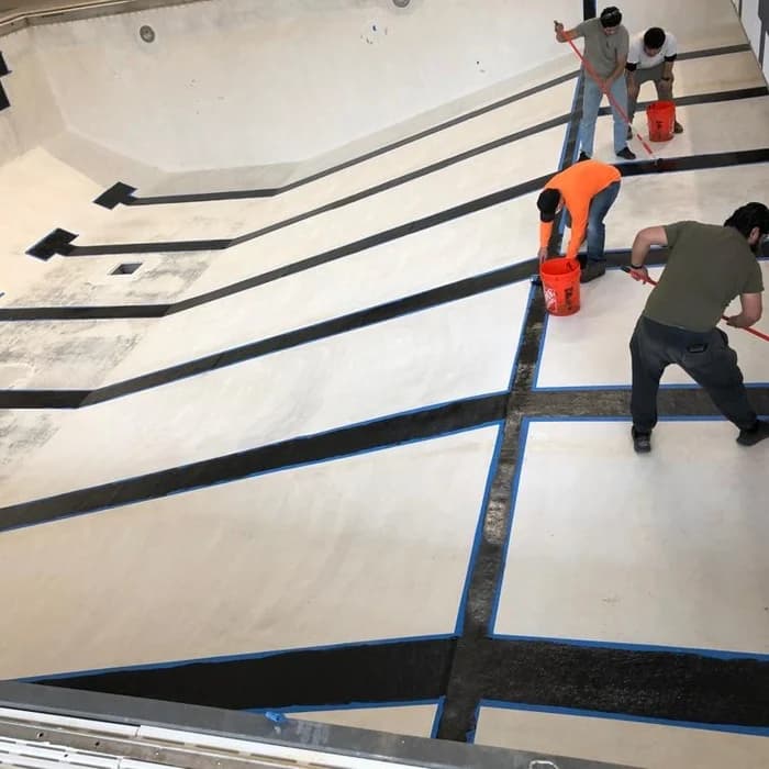 Pool shell mid-resurfacing with taped seams and plaster crew at work