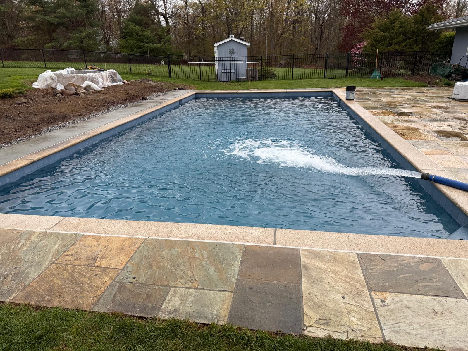 Finished pool being filled with water alongside a new bluestone patio